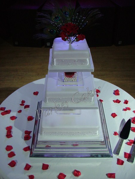 three tier wedding cake with pearls and peacock feathers