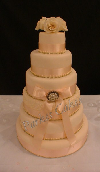 five tier peach wedding cake with diamante and brooch