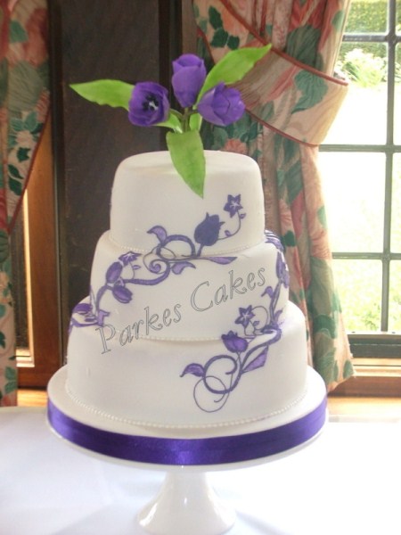 three tier white wedding cake with purple tulips