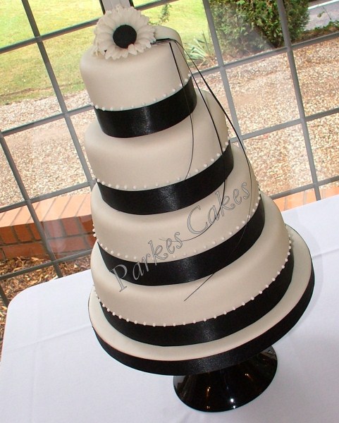 four tier black and white wedding cake with gerberras