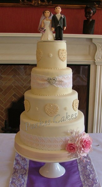 four tier ivory wedding cake with vintage lace, hearts and rose spray