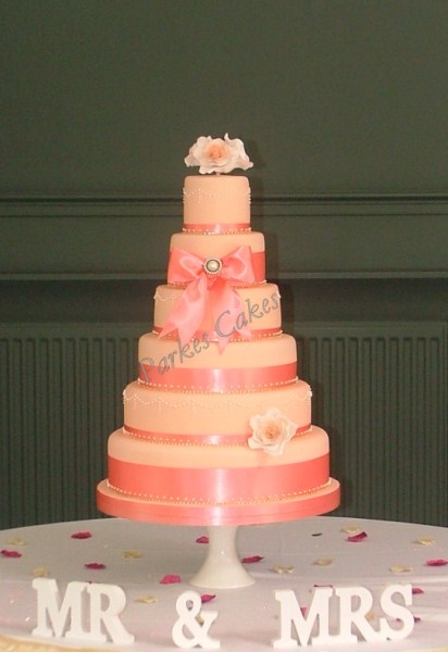 six tier coral wedding cake with gold diamante trim