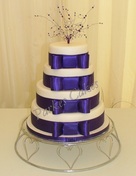 four tier wedding cake with cadbury purple ribbons and beaded topper